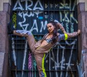 bailarina com macacão colorido posando em frente a uma porta verde de metal pichada